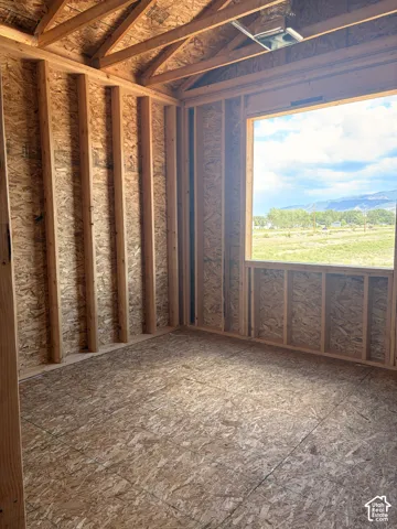 New construction framing with an expansive window, exposed rafter ceilings, and oriented strand board wall sheathing and subflooring