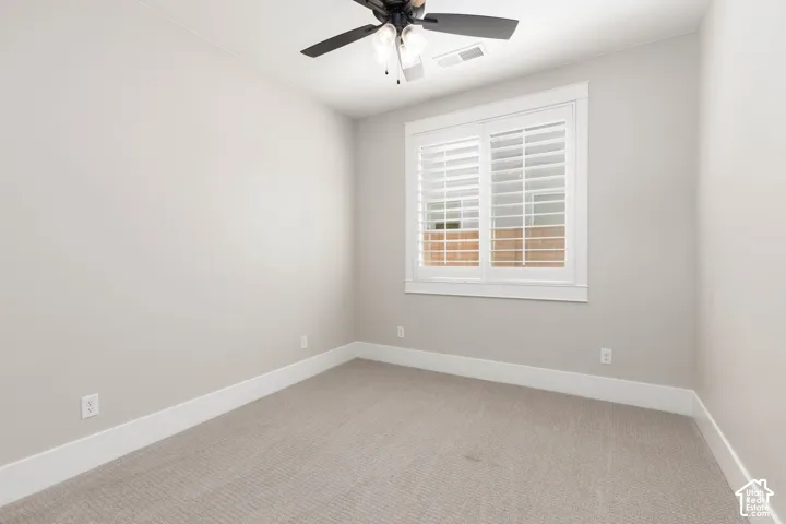 Neutral wall paint, plush carpeting, white window shutters, and a ceiling fan with integrated lighting