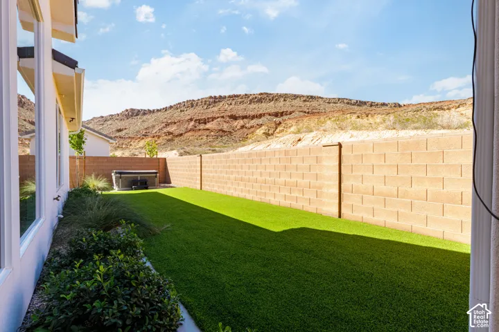 Backyard featuring a block privacy wall, artificial turf, and desert landscaping