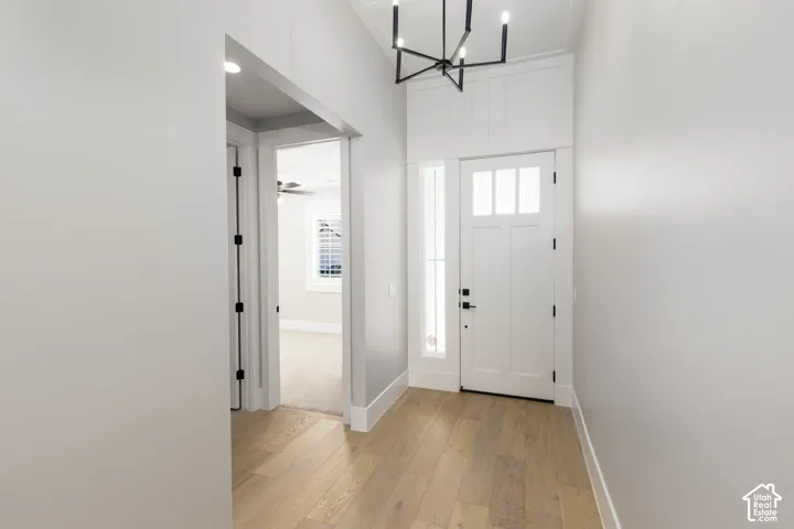 Bright entryway featuring wood-finish flooring, a contemporary chandelier, a craftsman-style door with sidelight, and white trim
