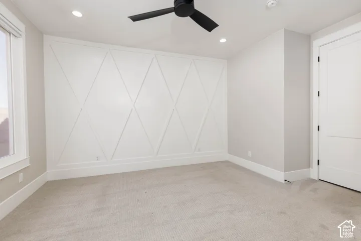Accent wall with geometric trim, recessed lighting, ceiling fan, carpeting, and white trim