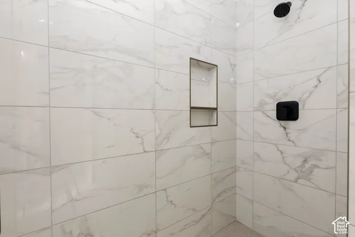 White tiled shower with a built-in niche, matte black shower head, and coordinating matte black single-handle control