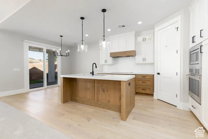 Modern kitchen featuring a wood-finish island, white cabinetry, stainless steel appliances, and wood-finish flooring