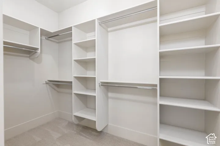Built-in closet system featuring white shelving, multiple hanging rods, and light-colored carpet