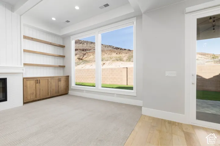 Living area featuring a built-in fireplace, natural wood shelving, and wood-finish flooring