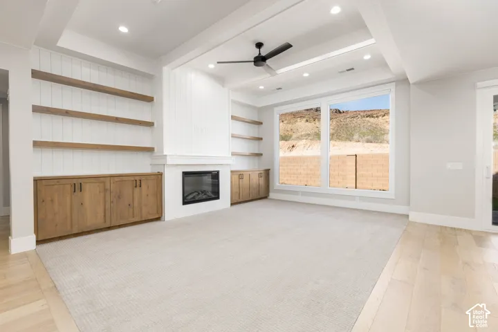 Built-in cabinetry with wood-finish shelving, an electric fireplace with a tile surround, a tray ceiling with recessed lighting, and expansive windows