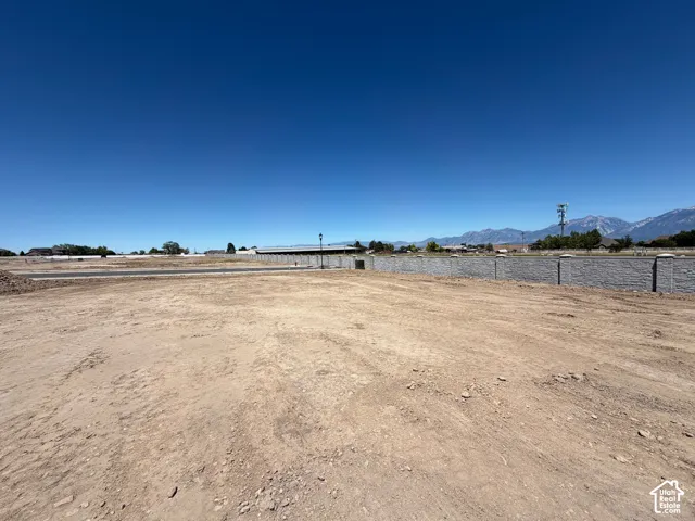 Expansive undeveloped lot featuring a gray block retaining wall and distant mountain range