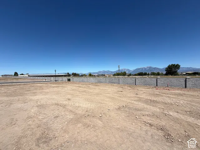 Level, undeveloped lot with a perimeter retaining wall and street lamp