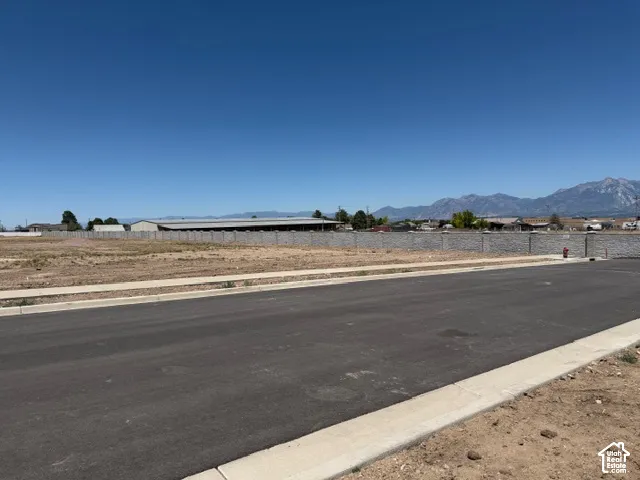 Cleared lot with an asphalt road, concrete sidewalk, and a retaining wall