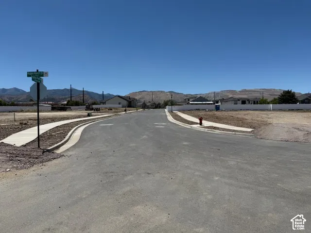 Paved streets with concrete sidewalks and curbs, complemented by distant mountain scenery