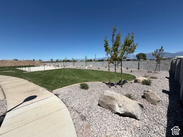 Expansive green space featuring a manicured lawn, established landscaping, and a concrete pathway