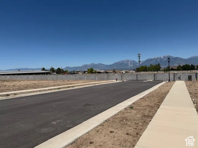 Paved road and sidewalk with concrete curb, retaining wall, and street lamp