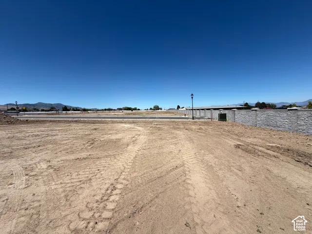 Expansive graded lot featuring a stone-finish perimeter wall, street lamp, and paved road access