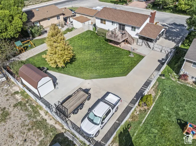 Expansive concrete driveway, detached storage shed, concrete patio area, upper level wood deck, and mature landscaping