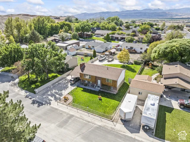 Expansive property featuring a detached outbuilding, established landscaping, mountain backdrop, and paved driveway