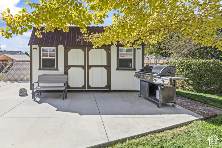 Outdoor shed with a brown metal roof, white siding, and two windows