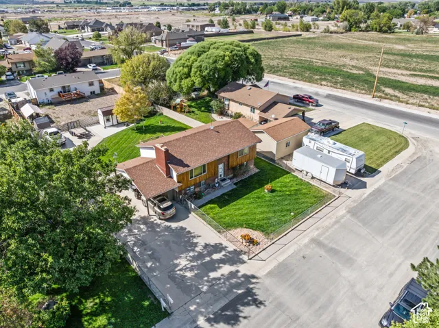 Large corner lot with a manicured front lawn, established trees, and a paved driveway