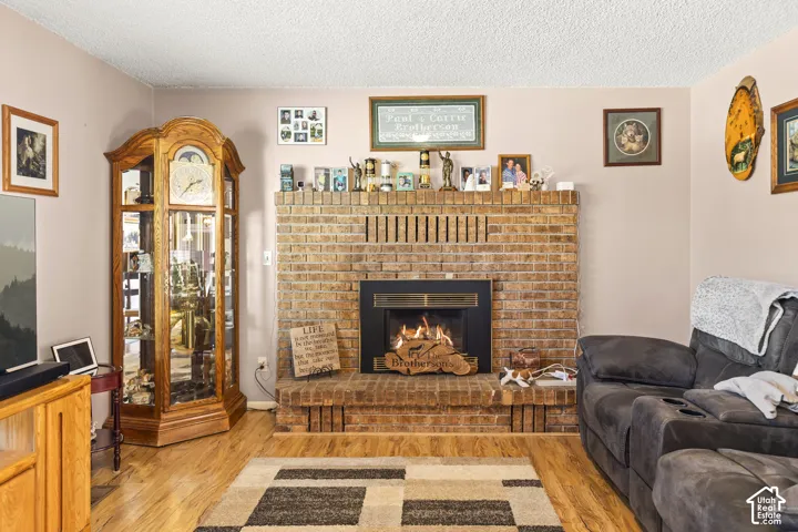 Brick fireplace with a black firebox, wood-finish flooring, and light-toned walls
