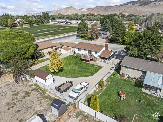 Expansive property featuring a paved driveway, a manicured lawn, a raised wood deck, and multiple storage sheds