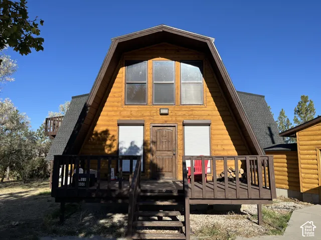 A-frame structure featuring log siding, a dark shingle roof, and a raised wooden deck with railings