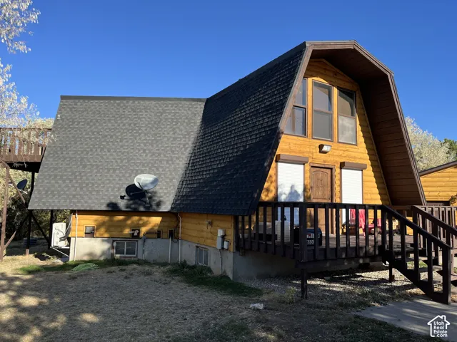 A-frame exterior with wood siding, dark shingle roof, and an elevated wood deck