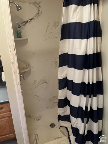 Shower with a textured wall surround, integrated shelving, and a chrome showerhead
