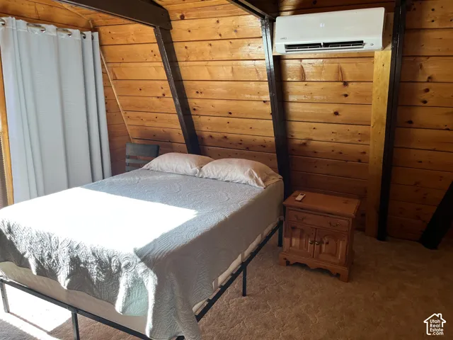Vaulted wood-paneled ceiling, wood-finish flooring, and built-in wall-mounted air conditioning unit