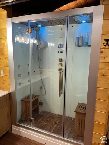Enclosed shower with multiple shower heads, integrated control panel, and built-in shelving