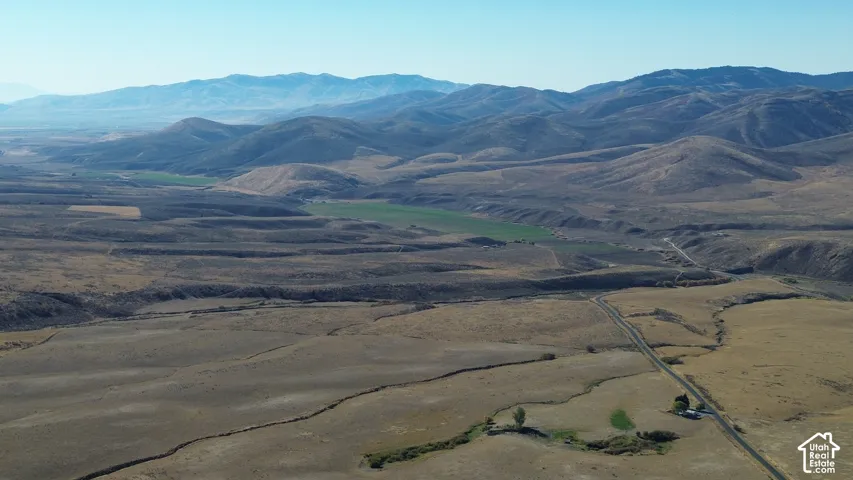 Expansive landscape featuring distant mountains, open terrain, and a visible roadway