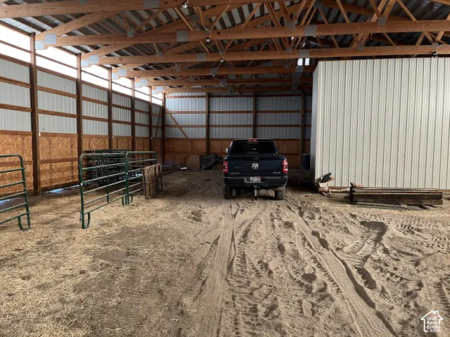 Expansive barn structure featuring exposed wood trusses, corrugated metal siding, and a large open interior