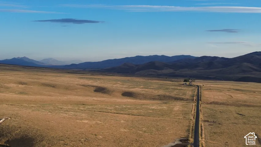 Expansive land featuring a long, unpaved road and distant mountain ranges