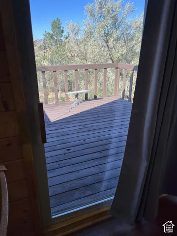 Wood-paneled interior wall, sliding glass door, wooden deck with railing, and natural landscaping