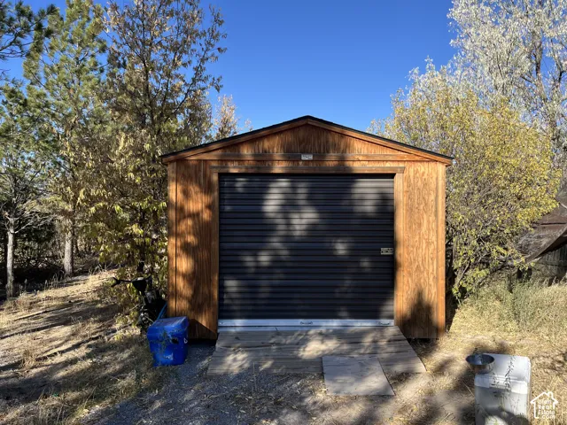 Wood-sided storage shed with a dark roll-up door and a pitched roof