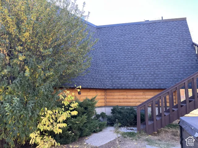 Dark gray shingle roof, log-style siding, and exterior wood staircase