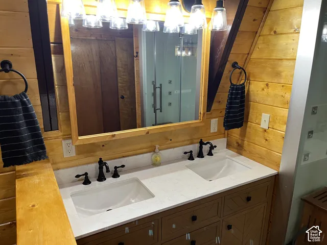 Dual undermount sinks with matte black fixtures, set into a light-toned countertop, and illuminated by a vanity light bar