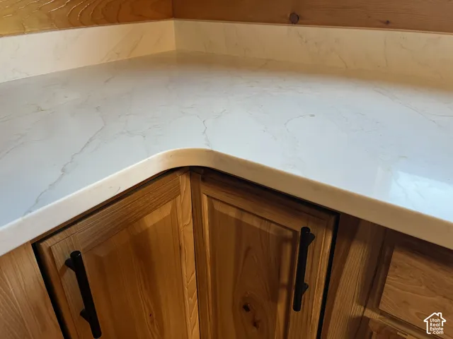 Light-toned countertop with subtle veining, wood-finish cabinetry, and black hardware