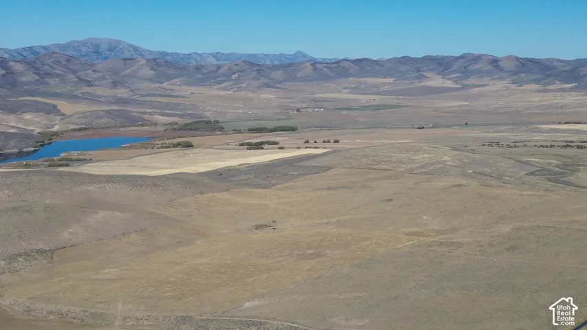 Expansive land featuring a natural body of water, distant mountains, and varied terrain