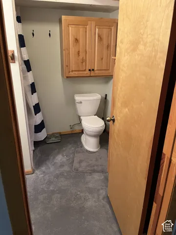 Wall-mounted wood-finish cabinetry, floor-mounted toilet, and light-toned wall paint