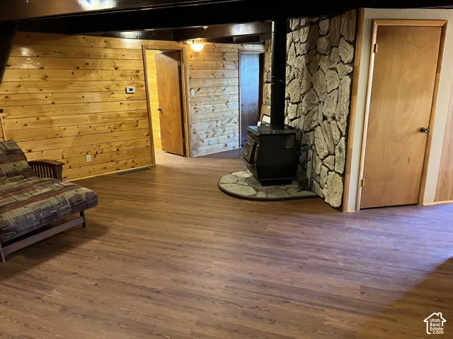 Wood-finish flooring, wood plank walls, and a stone-clad wood-burning stove with a stone hearth