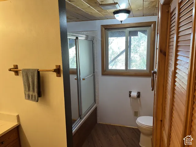 Wood-plank ceiling, wood-finish flooring, wood-framed window, sliding glass shower enclosure, and louvered wood doors