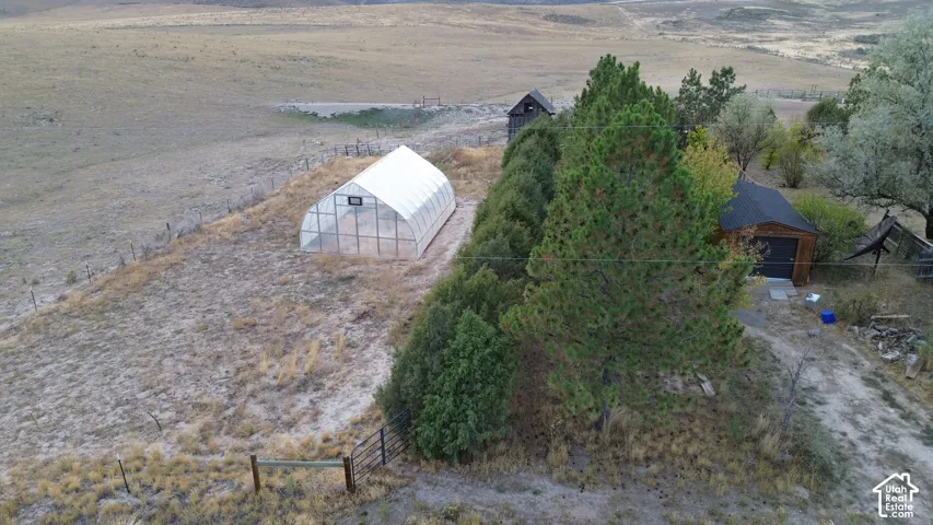 Detached outbuilding, freestanding greenhouse structure, natural terrain, and mature trees