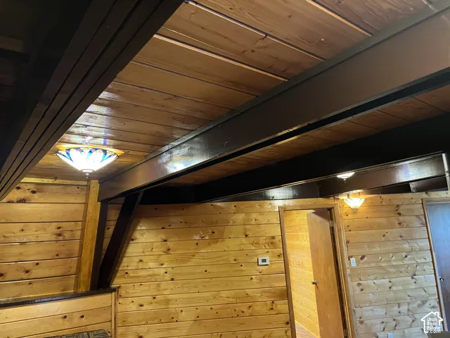 Wood plank walls, wood plank ceiling, exposed dark wood beams, and decorative flush-mount lighting