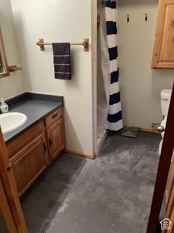 Vanity with a built-in sink and dark countertop, wood-finish cabinetry, and a shower area