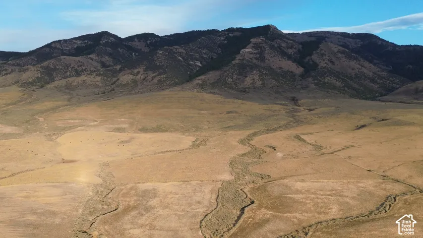 Expansive open terrain with natural contours, highlighted by distant mountain ranges and a clear sky
