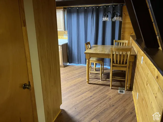 Wood-finish flooring throughout, light wood-tone cabinetry, and a dark-toned ceiling beam