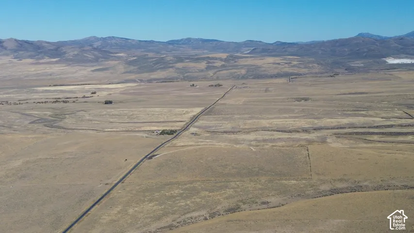 Expansive open land with distant mountain ranges and a long, straight road