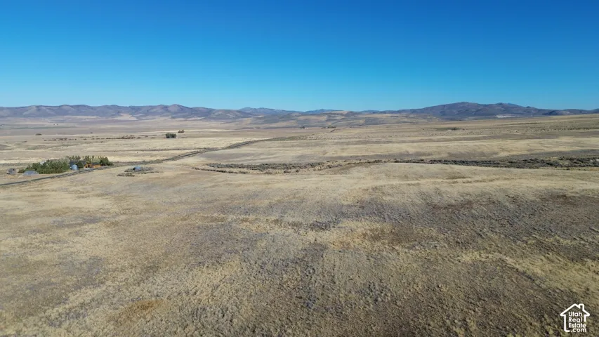 Expansive dry grassland acreage with distant mountain ranges under a clear sky