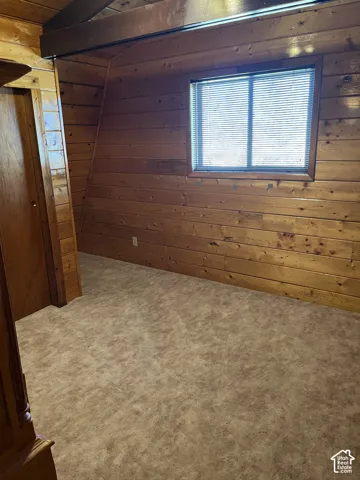 Window with horizontal blinds, wood-paneled walls, and a wood-finish ceiling beam