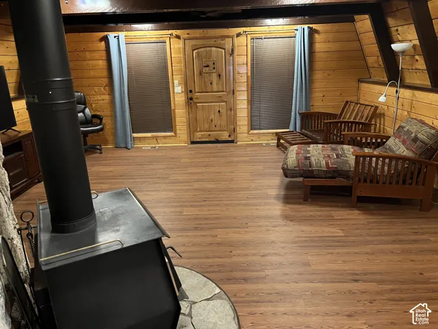 Wood-finish flooring, wood plank walls, and a freestanding wood-burning stove with a stone surround