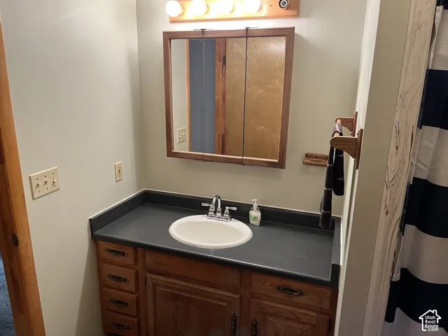 Wood-finish vanity with drawer and cabinet storage, featuring a light countertop and an integrated sink with a chrome faucet